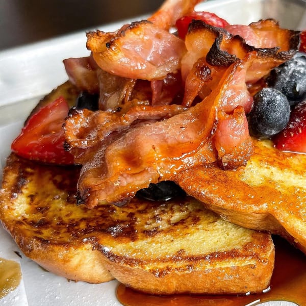 BarleyBean's French toast topped with crispy bacon, fresh blueberries, strawberries, and syrup.