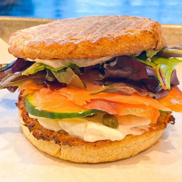 A BarleyBean cafe sandwich with smoked salmon, cream cheese, cucumbers, capers, and mixed greens.