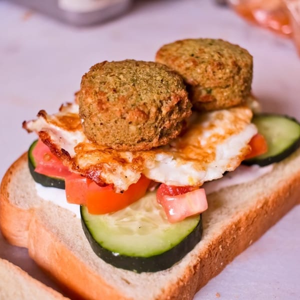 BarleyBean's open-faced sandwich with falafel, fried egg, tomatoes, and cucumbers on toast.