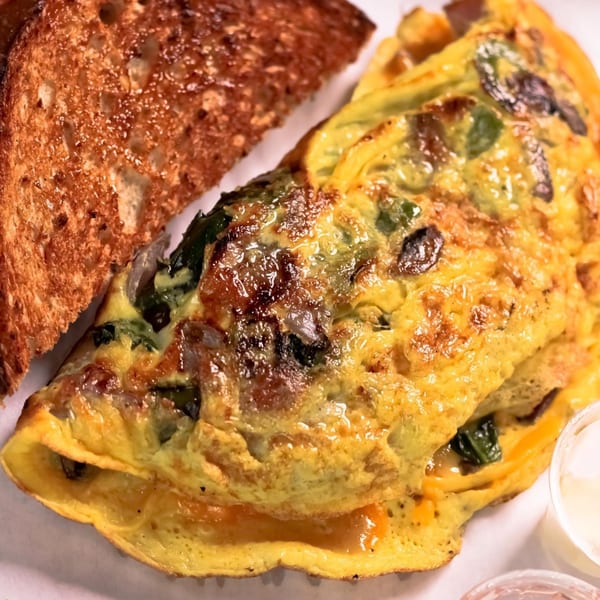 BarleyBean's fluffy omelet filled with spinach and cheese, served with a side of toasted bread.